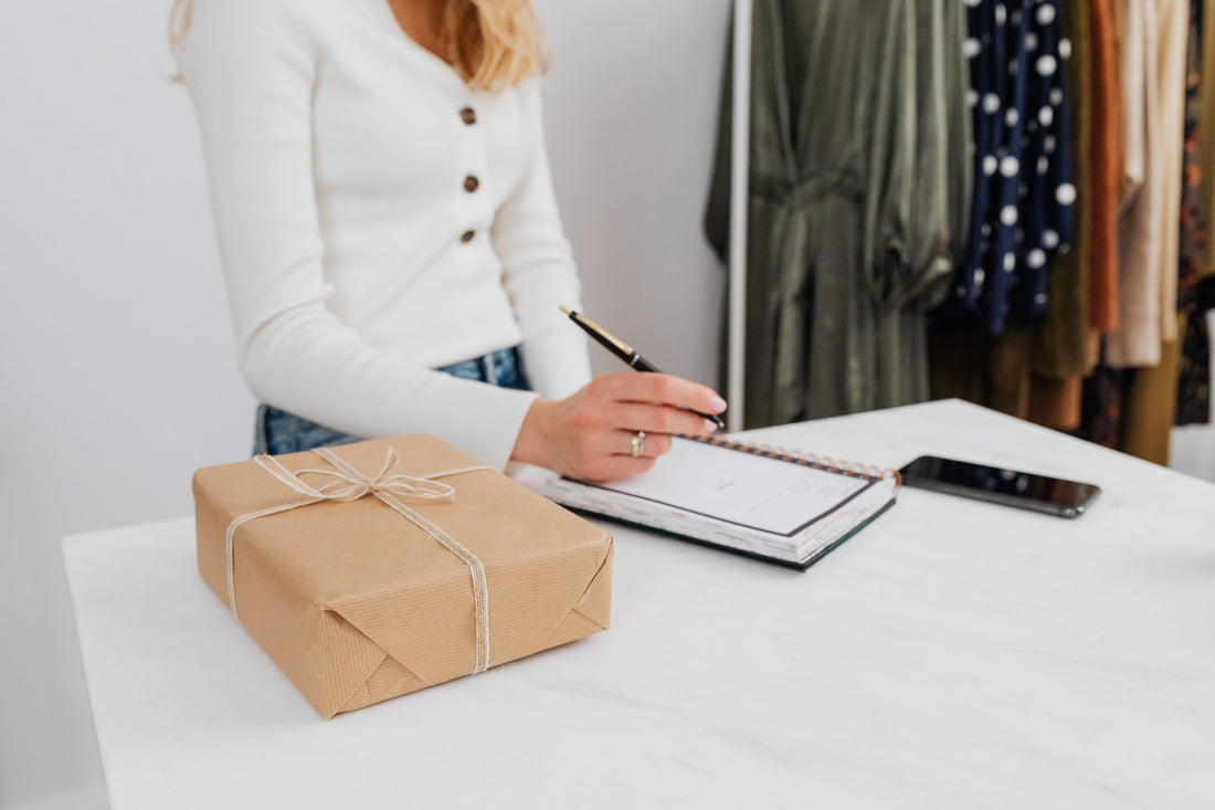 A wrapped gift box beside a notebook and pen, a stationery gifting scene