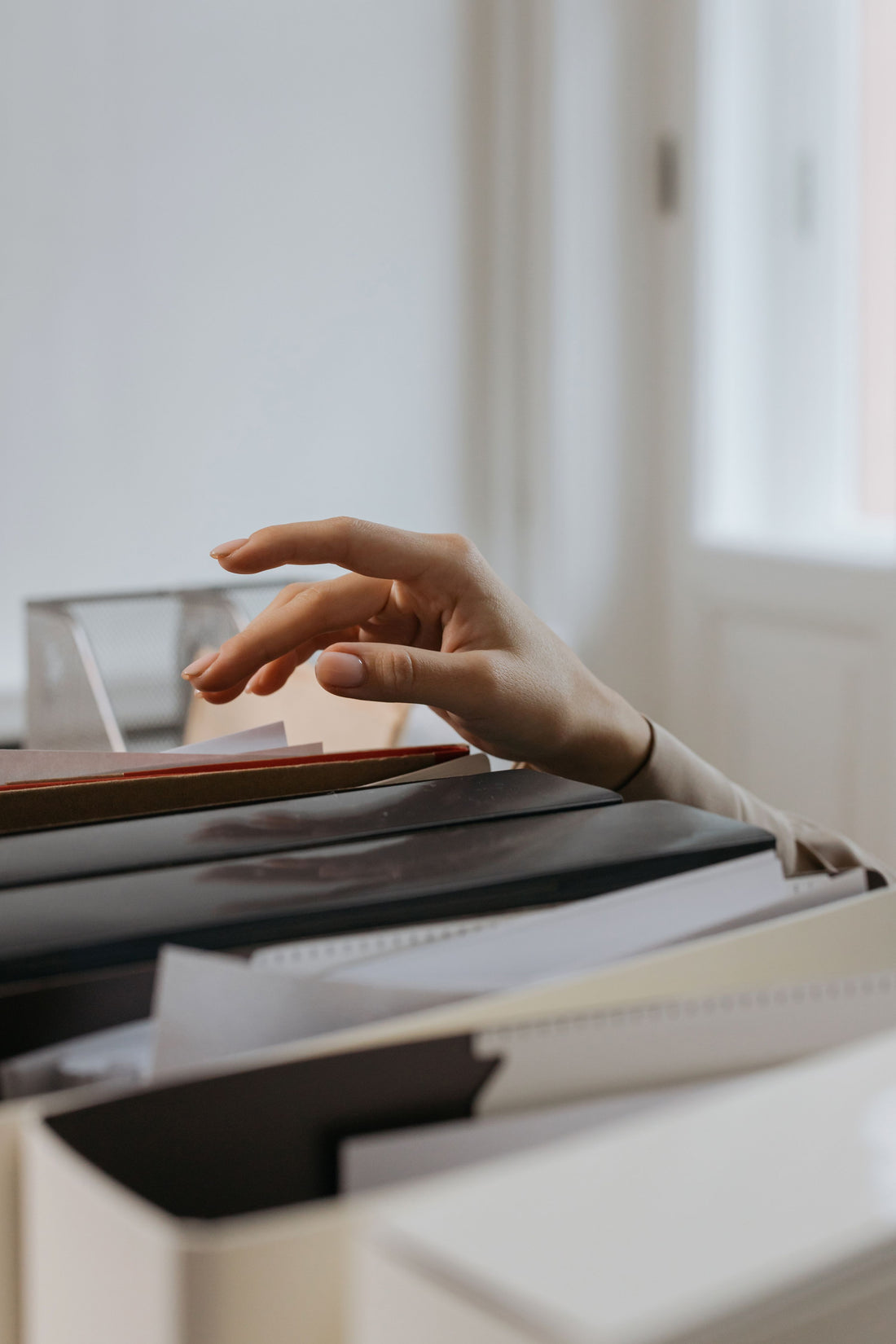 Hand reaching into an open file drawer full of folders