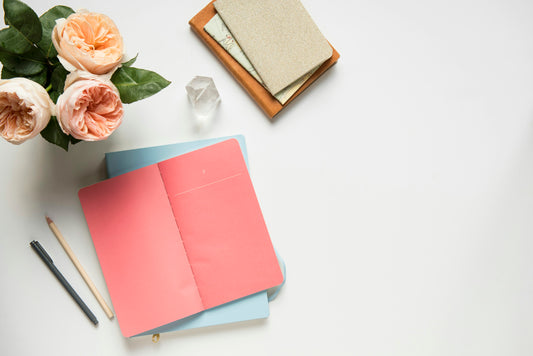 Open notebook with lined pages on a desk with fresh flowers and a pen