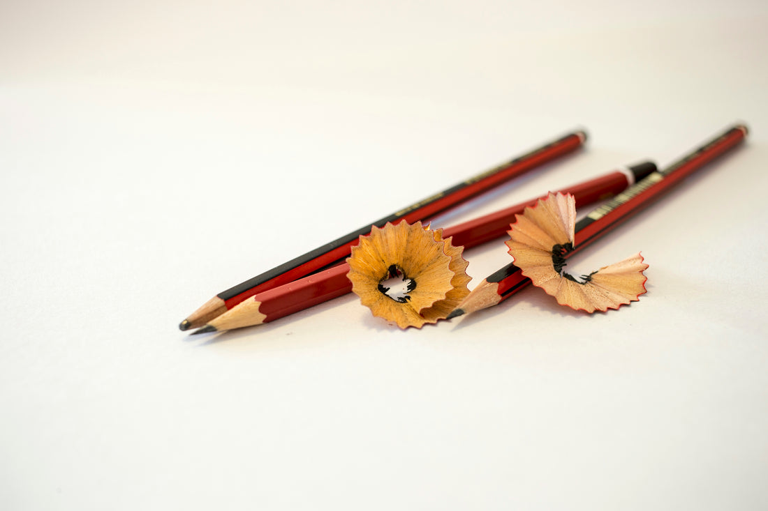Red pencils with curled wood shavings on a white surface